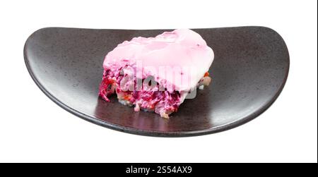 Dressed Hering russischer Salat auf schwarzer Platte isoliert auf weißem Hintergrund. Dressed Hering russischer Salat auf schwarzem Teller Stockfoto