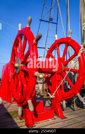 Rotes Holzrad auf einem antiken Schiff. Rotes Steuerrad auf einem antiken Schiff Stockfoto