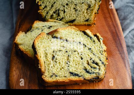 Matcha Black Sesam Babka Nahaufnahme: Geschnittenes Brot mit grünem Tee und süßem Sesam-Dessertbrot auf einem hölzernen Schneidebrett Stockfoto