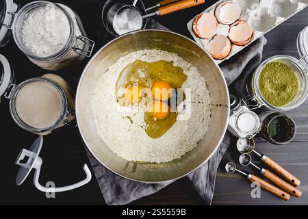 Zutaten für Matcha-Brot in einer Schüssel: Mehl, Grüntee-Pulver, Eier und Vanillebohnenpaste mit anderen Zutaten und Küchenutensilien Stockfoto
