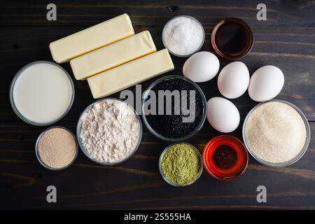 Matcha Black Sesam Babka Zutaten auf einem Holztisch: Grünes Teepulver, Mehl, Eier, Honig und mehr direkt über rustikalem dunklem Holzhintergrund Stockfoto