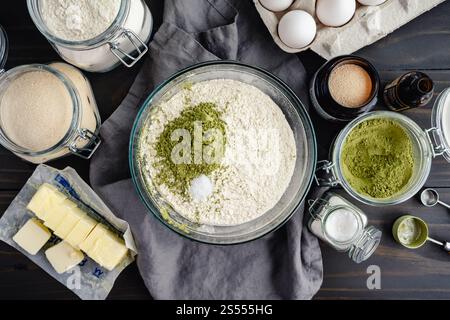 Ungemischte trockene Zutaten für Matcha-Brot: Mehl, Grüntee-Pulver, Zucker und Salz in einer Glasrührschüssel mit anderen Brotzutaten Stockfoto
