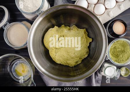 Grüner Matcha-Brotteig in einer Mischschüssel Nahaufnahme: Unaufgestellter grüner Tee-Babka-Teig umgeben von anderen Babka-Zutaten Stockfoto