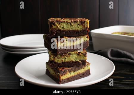 Gestapelte Matcha Cheesecake Brownies Seitenansicht: Profil aus dunkler Schokolade Brownies mit grünem Tee Frischkäse Füllung gestapelt auf weißem Dessertteller Stockfoto