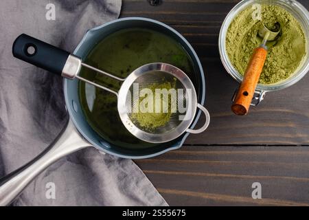 Sieben von Grüntee-Pulver in einfachen Sirup: Matcha-Pulver wird in einen Topf aus frisch zubereitetem Zuckersirup gesiebt Stockfoto