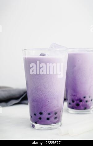 Zwei Gläser Purple Sweet Potato Bubble Tea: UBE boba mit Eiswürfeln und klaren Silikonhalmen auf weißem Hintergrund Stockfoto