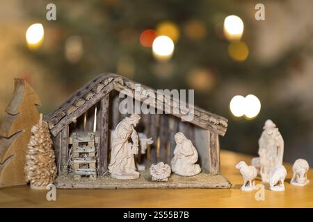 Stall mit der Heiligen Familie, Hirte und Schafe kommen zum Kinderbett, Krippenszene, Weihnachtsbaum im Hintergrund Stockfoto