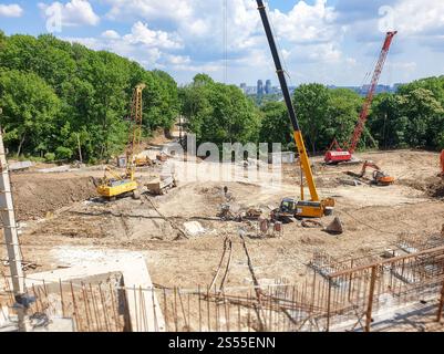 Foto von schweren Lkw und Baukränen, die an sonnigen Tagen auf der Baustelle arbeiten. Bild von schweren Lkw und Baukränen, die am arbeiten Stockfoto
