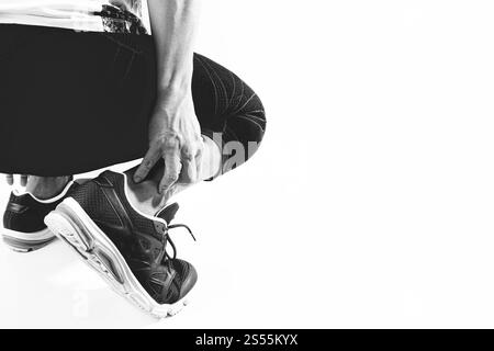 Läufersportler mit Schmerzen am Knöchel mit gebrochenem, verdrehtem Gelenk, Laufsportverletzung und Athletischer Mann, der den Fuß aufgrund einer Verstauchung berührt, schwarz-weiß Stockfoto