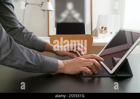 Geschäftsmann oder Designer mit digitalen Tablet-Computer auf schwarzen Schreibtisch im modernen Büro Stockfoto