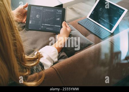 Brünette Frau mit digitalen Talet und Laptop-Computer auf Sofa im Wohnzimmer Stockfoto