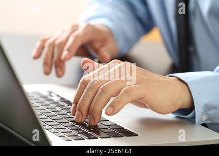 Nahaufnahme von Geschäftsmann Eingabe Tastatur mit Laptop-Computer auf hölzernen Schreibtisch im modernen Büro Stockfoto