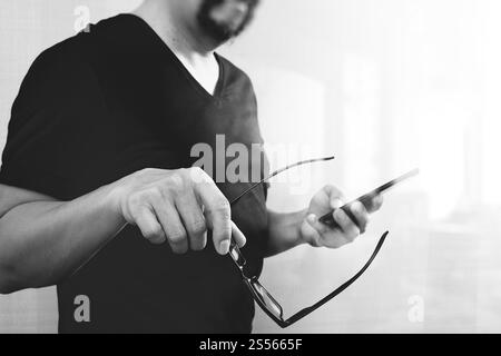 Designer Hand hält Brillen, mit Smartphone, schwarz / weiß Stockfoto