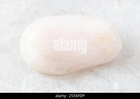 Nahaufnahme der Probe des natürlichen Minerals aus der geologischen Sammlung - Polierter Petalit-Stein auf weißem Marmorhintergrund Stockfoto