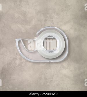 Transparenter Abroller mit Scotch-Klebeband, isoliert auf Betonhintergrund. Scotch Tape Spender isoliert auf Betonhintergrund Stockfoto