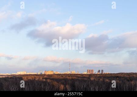 Wolken im blauen Sonnenuntergang Himmel über Stadtpark und Aussicht Des sonnendurchfluteten Wohnviertels am Horizont am Frühlingsabend Stockfoto