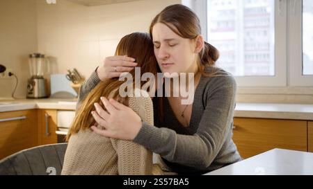 Die junge Mutter tröstet und tröstet ihre verärgerte Tochter im Teenageralter. Eltern, die das Kind unterstützen und trösten. Stockfoto