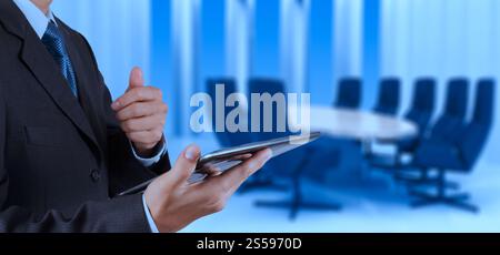Geschäftsmann Hand mit Tablet-Computer und Hintergrund des Besprechungsraums Stockfoto