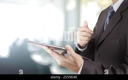 Geschäftsmann Hand mit Tablet PC und Office-Hintergrund Stockfoto