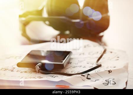 Closeup Jack smart phone mit Kopfhörer auf Noten-Papier mit flachen DOF gleichmäßig abgestimmt auf Schreibtisch aus Holz Stockfoto