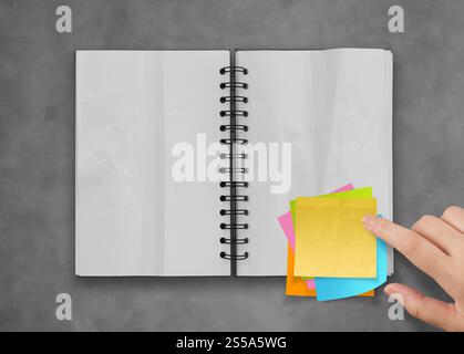 Haftnotizen mit offenen leere Notizbuch auf Schreibtisch Top Textur Stockfoto