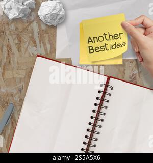 eine weitere Idee Wort Haftnotizen mit leere offene Notizbuch über Recycling Holz Tischplatte Stockfoto