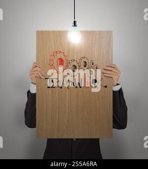 Mann zeigt Poster von Hand gezeichnet Wort TEAMWORK mit wachsendem Lightbulbon Holzbrett als Konzept Stockfoto