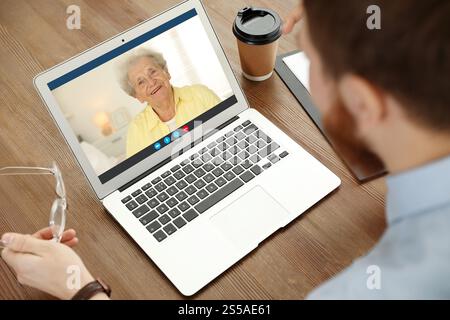 Großmutter und Enkel sprechen per Videoanruf auf dem Laptop. Mann, der am Tisch Computer benutzt Stockfoto
