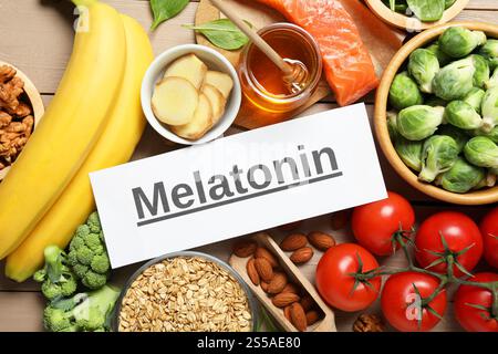 Wort Melatonin und verschiedene Produkte auf Holztisch, flach gelegt Stockfoto