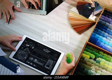 Draufsicht von zwei Kollegen Innenarchitekten, die Daten mit einem digitalen Tablet und einem neuen modernen Computer-Laptop mit Beispielmaterial auf einem Holztisch diskutieren Stockfoto