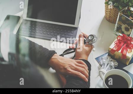 Geschenk geben, Arzt Hand mit Kreditkarte und Hand mit Geschenk. Geschenklieferung, Überraschung, Laptop und Smartphone auf dem Schreibtisch, Filter Stockfoto