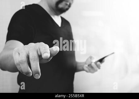 Geschäftsmann Hand einen imaginären Taste halten, Smartphone, grafische virtuellen digitalen Bildschirmsymbole, Diagramm, Diagramm, schwarz weiß Stockfoto