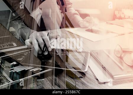 Doppelbelichtung Website Designer Holding Smartphone und funktionierende Computer digital-Tablette auf Holztisch, London Architektur buldings Stockfoto