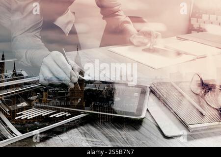 Doppelbelichtung Website Designer Holding Smartphone und funktionierende Computer digital-Tablette auf Holztisch, London Architektur buldings Stockfoto