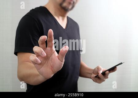 Geschäftsmann Hand einen imaginären Taste halten, Smartphone, digitale Grafik virtuelle Bildschirmsymbole, Diagramm, Diagramm Stockfoto