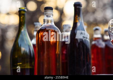 Nahaufnahme - Gruppe von Glasflaschen mit hausgemachten Beeren- und Fruchtweinen. Natürlich. Stockfoto