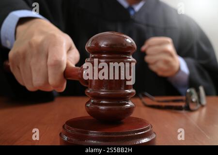 Recht und Gesetz-Konzept. Männlichen Richter in einem Gerichtssaal auffällig die Hammer, arbeiten mit digitalen Tablet Computer Docking-Tastatur auf Holztisch Stockfoto