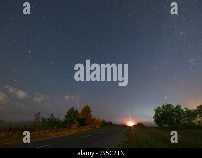 Komet Neowise C2020 F3, wie er im Sommerhimmel über einer Wiese in der Nähe der Landstraße, Region Lviv, Ukraine fliegt. Stockfoto