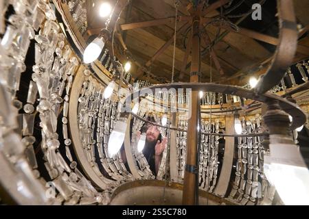 Jason Cardwell vom Tower Ballroom Team inspiziert das Innere eines 1-Tonnen-Kronleuchters, der von der Decke in ein speziell gefertigtes Gerüst abgesenkt wurde, bevor die beiden weltberühmten Kronleuchter im Blackpool Tower in Lancashire jährlich gereinigt und restauriert werden. Während die beiden Kronleuchter abgesenkt werden, wird ihr einzigartiger Seilmechanismus - der weltweit einzige seiner Art - zum ersten Mal in der Geschichte der Ballsäle ersetzt, ein Projekt, das in den nächsten Wochen abgeschlossen wird. Bilddatum: Dienstag, 14. Januar 2025. Stockfoto