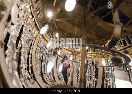 Jason Cardwell vom Tower Ballroom Team inspiziert das Innere eines 1-Tonnen-Kronleuchters, der von der Decke in ein speziell gefertigtes Gerüst abgesenkt wurde, bevor die beiden weltberühmten Kronleuchter im Blackpool Tower in Lancashire jährlich gereinigt und restauriert werden. Während die beiden Kronleuchter abgesenkt werden, wird ihr einzigartiger Seilmechanismus - der weltweit einzige seiner Art - zum ersten Mal in der Geschichte der Ballsäle ersetzt, ein Projekt, das in den nächsten Wochen abgeschlossen wird. Bilddatum: Dienstag, 14. Januar 2025. Stockfoto