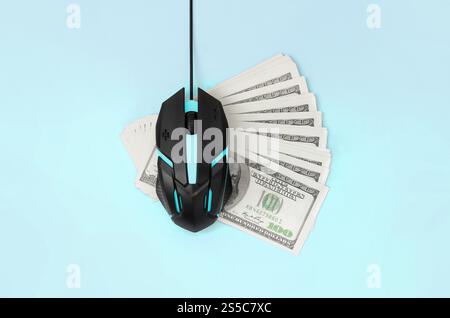 Computermaus auf vielen Dollarscheine. Pay-per-Click und Autoclicker-Konzept. Einnahmen im Internet. Flache Draufsicht auf pastellblauem Hintergrund. Stockfoto