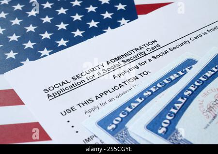 US-amerikanische Sozialversicherungsnummernkarten liegen auf Antrag der Sozialversicherungsverwaltung auf US-Flagge Nahaufnahme. Sozialversicherung der Vereinigten Staaten Stockfoto
