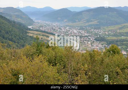 Eine wunderschöne Aussicht auf das Dorf Mezhgorye, Karpaten Region. Eine Menge von Wohngebäuden durch hohe Wald Berge und lange Fluss umgeben Stockfoto