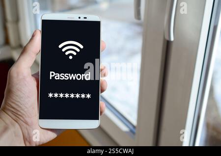 Eine Person sieht eine weiße Inschrift auf einem schwarzen Smartphone-Display, das in ihrer Hand hält. Passwort Stockfoto