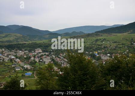 Eine wunderschöne Aussicht auf das Dorf Mezhgorye, Karpaten Region. Eine Menge von Wohngebäuden durch hohe Wald Berge und lange Fluss umgeben Stockfoto