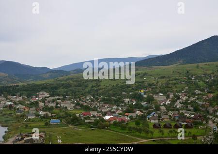 Eine wunderschöne Aussicht auf das Dorf Mezhgorye, Karpaten Region. Eine Menge von Wohngebäuden durch hohe Wald Berge und lange Fluss umgeben Stockfoto