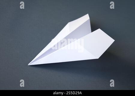 Weißes Papierflugzeug Origami isoliert auf einem leeren grauen Hintergrund. Weißes Papierflugzeug Origami isoliert auf grauem Hintergrund Stockfoto