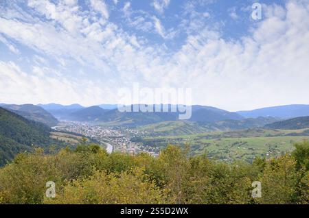 Eine wunderschöne Aussicht auf das Dorf Mezhgorye, Karpaten Region. Eine Menge von Wohngebäuden durch hohe Wald Berge und lange Fluss umgeben Stockfoto