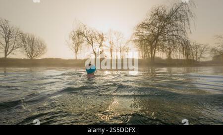 Stimmungsvolle Aufnahme einer einsamen weiblichen Wildnis, die an einem nebeligen Wintermorgen bei Sonnenaufgang in die Ferne schwimmt. York Stockfoto