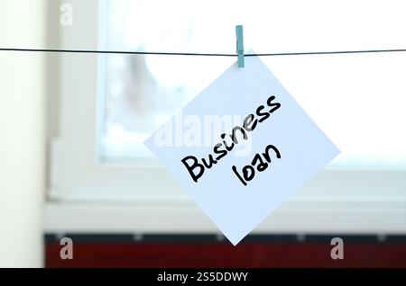 Geschäftsdarlehen. Die Notiz ist auf einem weißen Aufkleber geschrieben, der mit einem Kleiderschrank an einem Seil auf einem Hintergrund aus Fensterglas hängt Stockfoto